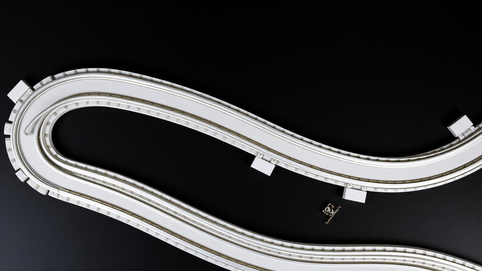 Modern LEGO plastic train track loop with a 9V metal-rail track piece for comparison on a dark surface